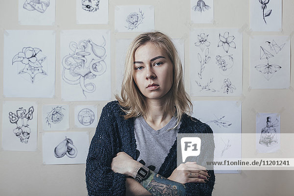 Porträt eines selbstbewussten Tätowierers,  der sich gegen Entwürfe im Atelier stellt