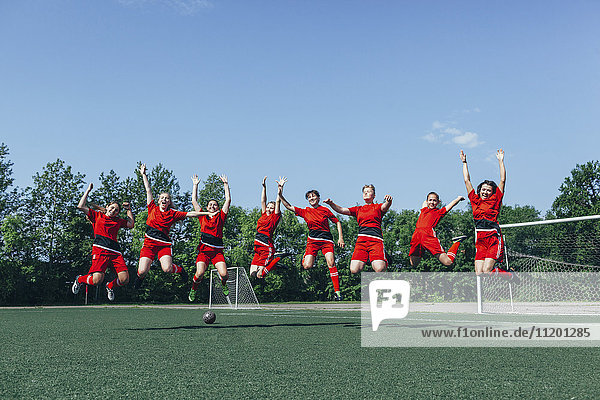 Fröhliche Fußballmannschaft jubelt auf dem Feld gegen den Himmel