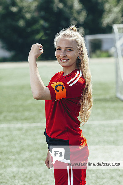 Confident soccer captain showing band with letter C on field