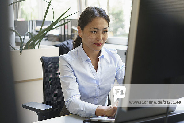 Confident smiling businesswoman using computer at creative office