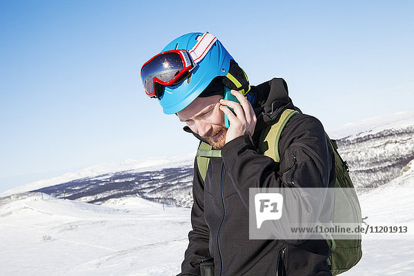 Skifahrer  der mit einem Mobiltelefon spricht