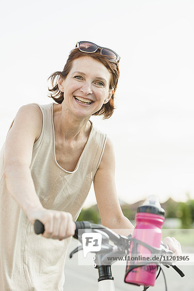 Porträt einer lächelnden Frau beim Radfahren gegen den klaren Himmel