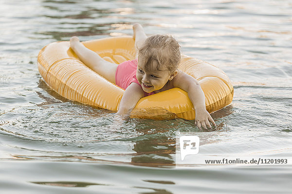 Happy girl floating on raft in lake