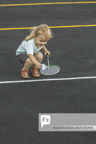 Glückliches Mädchen beim Spielen mit Badmintonschläger und Federball auf dem Spielplatz