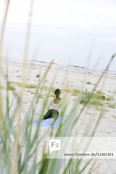 Young woman practicing yoga on beach