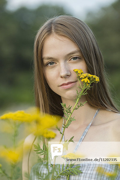 Porträt einer schönen Frau mit gelben Blumen im Park