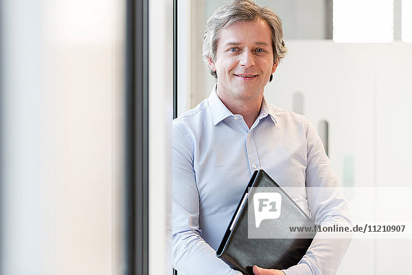 Portrait of smiling mature businesswoman holding file in office
