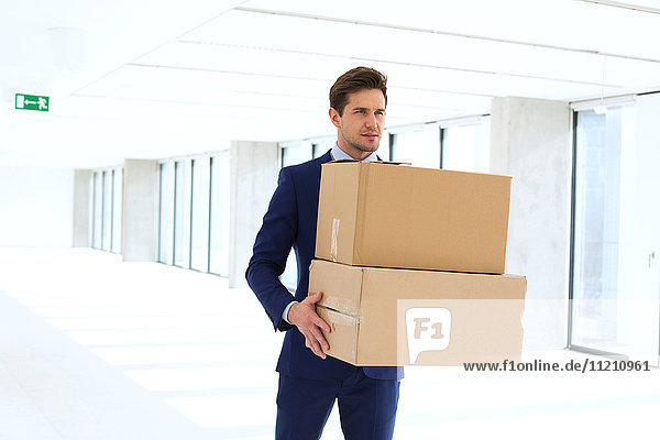 Young businessman carrying cardboard boxes in new office