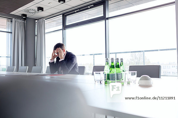 Mature businessman suffering from headache at conference table