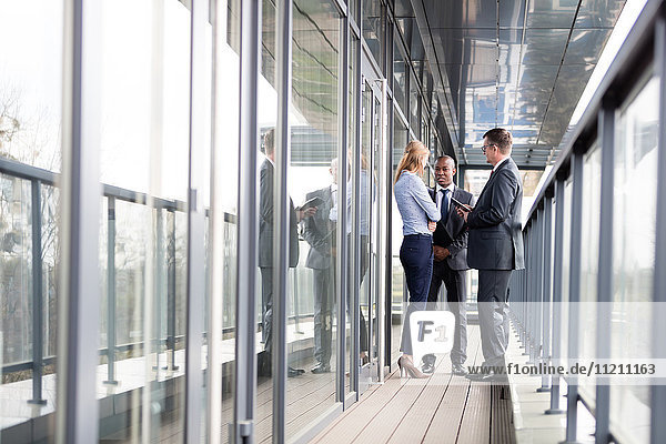 Full length of multi-ethnic business people discussing on office balcony