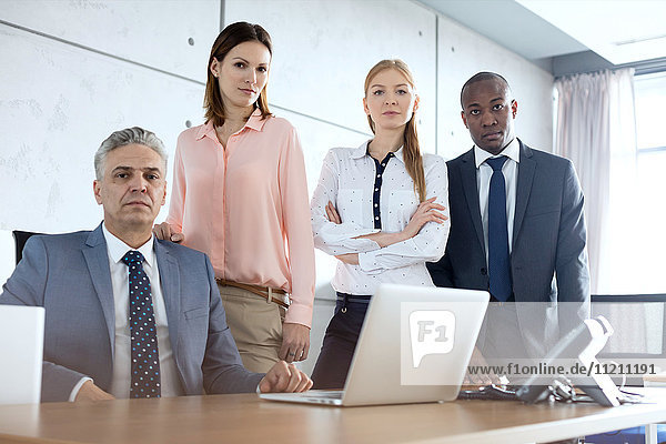 Portrait of confident multi-ethnic business people at desk in office
