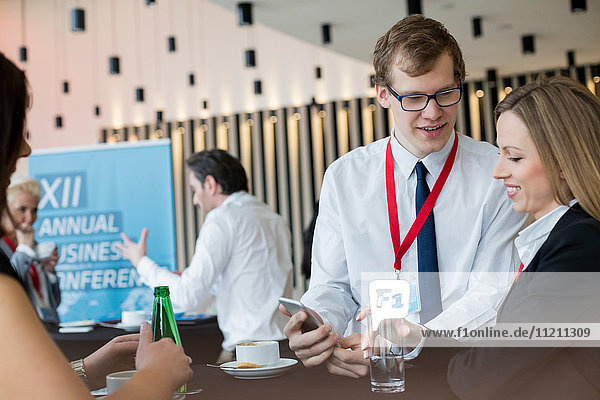 Geschäftsleute benutzen ein Smartphone während einer Kaffeepause im Kongresszentrum