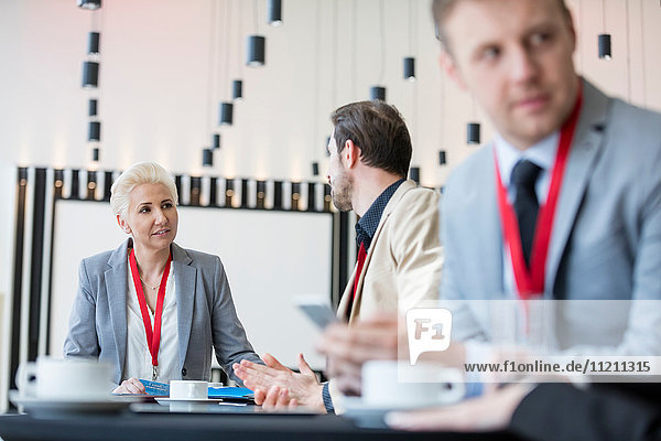 Confident businesswoman talking to businessman in convention center