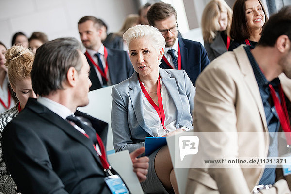 Businessman talking to businesswoman in seminar hall at convention center