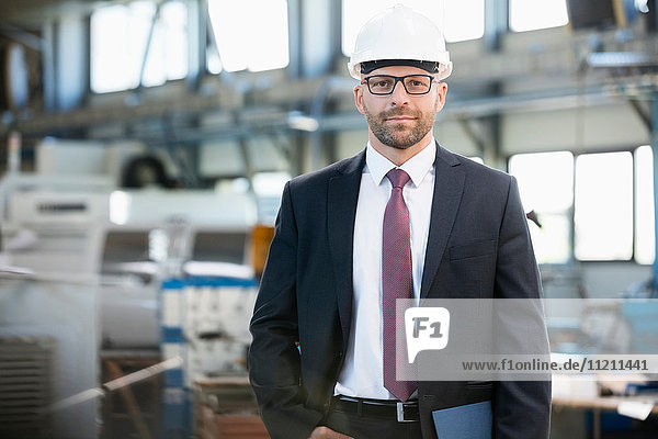 Portrait of confident mid adult businessman wearing hardhat in metal industry
