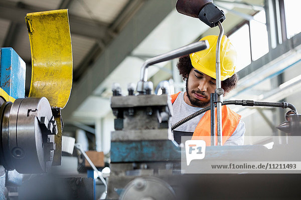 Low angle view of young manual worker working on machinery in metal industry