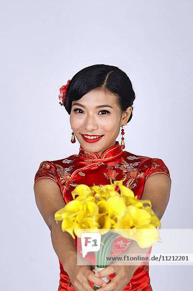 hübsche chinesische junge Frau hält einen Strauß gelber Narzissen