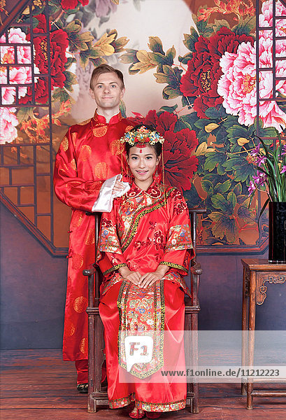 Mixed Race Bride and Groom in Studio wearing traditional Chinese wedding outfits
