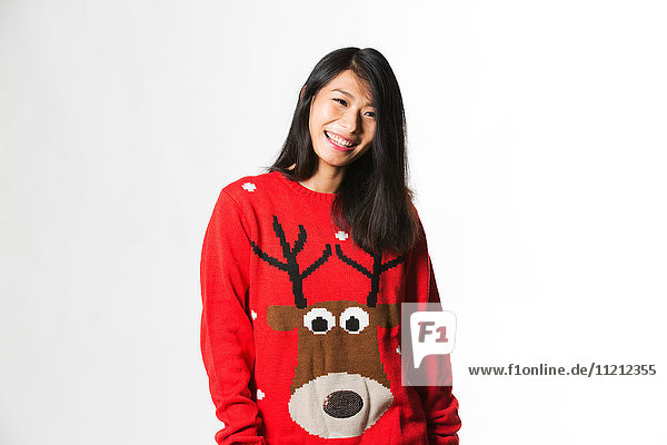 Portrait of Chinese woman in Christmas sweater standing in front of gray background