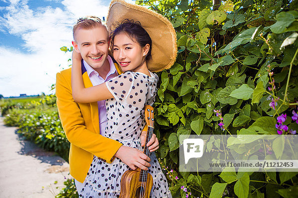 Porträt eines glücklichen Paares,  das sich bei Pflanzen umarmt