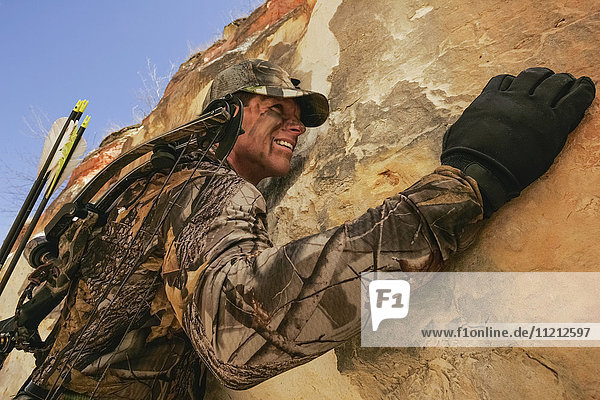 Extreme Bowhunting Hunter Climbing On Rocks With Bow On Back
