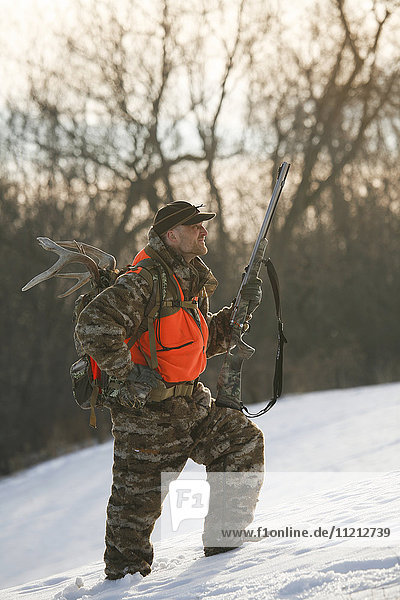 Jäger geht durch Schnee bei der Jagd auf Weißwedelhirsche