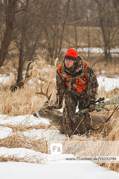 Whitetail Deer Hunter schleppt Hirsch aus dem Feld