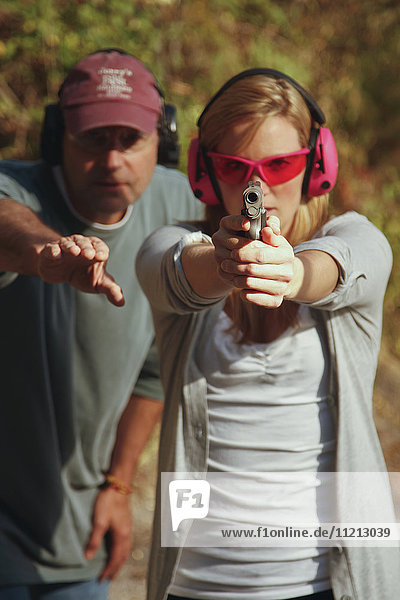 Frau wird auf dem Schießstand mit einer Handfeuerwaffe unterrichtet