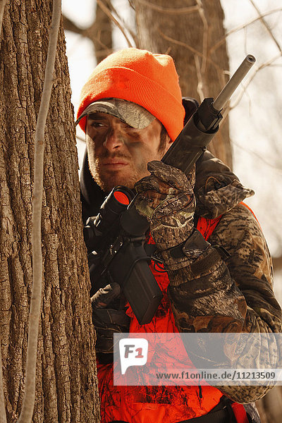 Whitetail Deer Hunter Waits Behind Tree