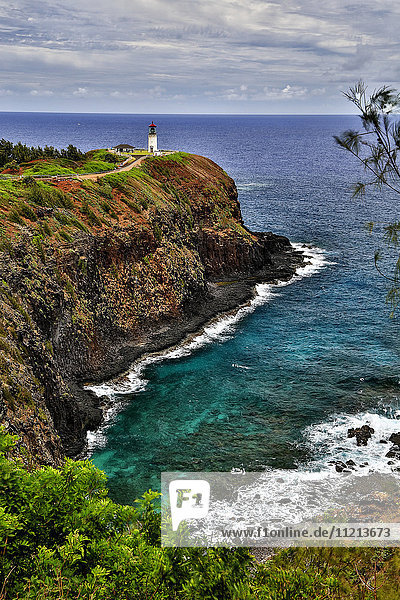 Ein Leuchtturm am Ende eines Weges oberhalb einer Klippe entlang der Küste  Kilauea Point; Hawaii  Vereinigte Staaten von Amerika'.