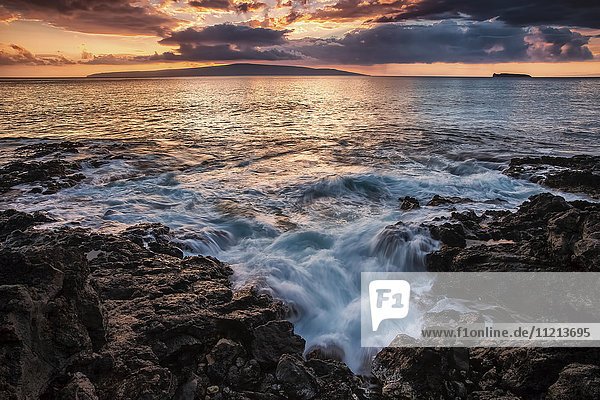 Wasser  das auf den schwarzen Lavafelsen am Ufer bei Sonnenuntergang gespült wird; Maui  Hawaii  Vereinigte Staaten von Amerika'.