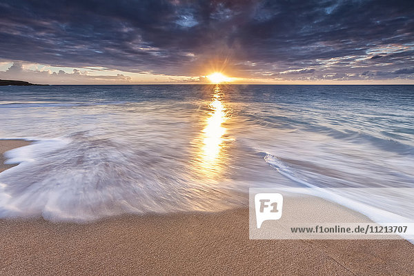 Sonnenlicht  das sich bei Sonnenuntergang auf dem Meer und dem Sandstrand spiegelt; Molokai  Hawaii  Vereinigte Staaten von Amerika'.