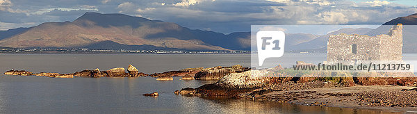 'Ruins of a building at the water's edge with mountains in the distance; Portmagee County Kerry Ireland'
