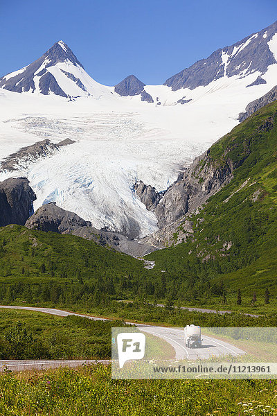 A pickup pulls a trailer down the Richardson Hwy with Worthington Glacier showing in background. Going north from Valdez  Alaska in Southcentral Alaska in Summer.