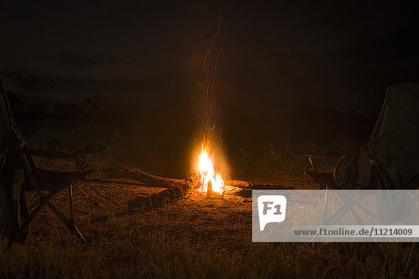 Zwei Campingstühle am nächtlichen Feuer; Botswana'.