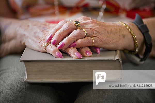 Die Hände einer älteren Frau sind über einem Buch mit festem Einband gefaltet; Devon  Alberta  Kanada'.