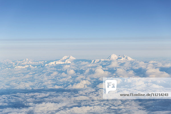 Aerial view of two snowcapped mountains in the Alaska Range peaking above the clouds  Anchorage  Southcentral Alaska  USA  Summer