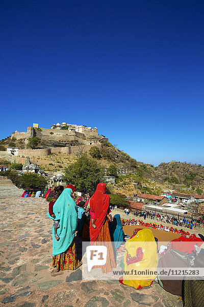 Frauen in farbenfroher traditioneller Rajasthani-Tracht vor einem verlassenen Rajput-Fort auf einem Hügel