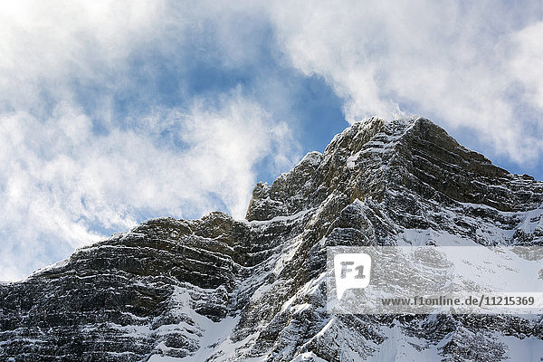 Schneebedeckter Berggipfel mit wogenden Wolken und blauem Himmel; Alberta  Kanada'.
