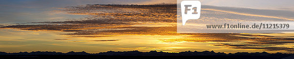 Panorama von farbenfrohen  dramatischen Wolken bei Sonnenuntergang mit der Silhouette von Bergen am Horizont; Calgary  Alberta  Kanada'.