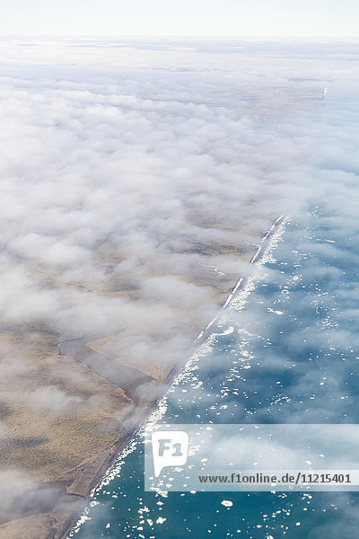 Luftaufnahme der in eine dünne Wolkenschicht gehüllten North-Slope-Küste  im Arktischen Ozean treibende Eisberge; Deadhorse  Alaska  Vereinigte Staaten von Amerika'.