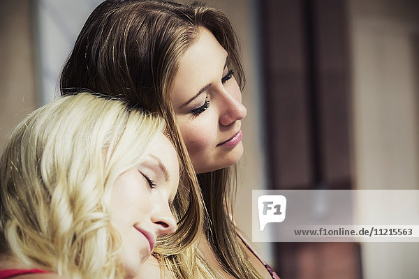 'Two beautiful young women taking a break from shopping and resting their heads on each other; Edmonton  Alberta  Canada'