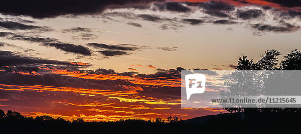 Dramatischer Himmel bei Sonnenuntergang mit Silhouette von Bäumen und Landschaft; Foster,  Quebec,  Kanada'.