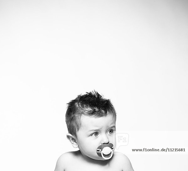 'Portrait of a young boy with a pacifier in his mouth against a white background; Saskatchewan  Canada'