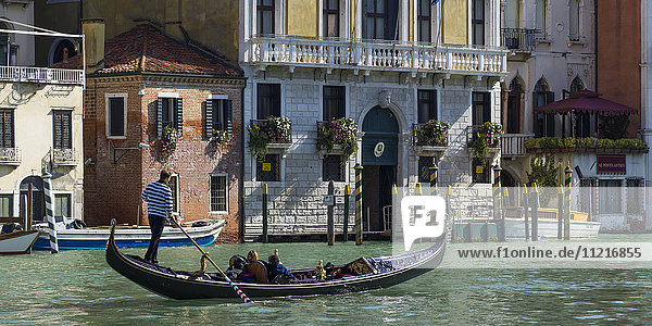 Gondel in einem Kanal mit Gondoliere im gestreiften Hemd; Venedig  Italien