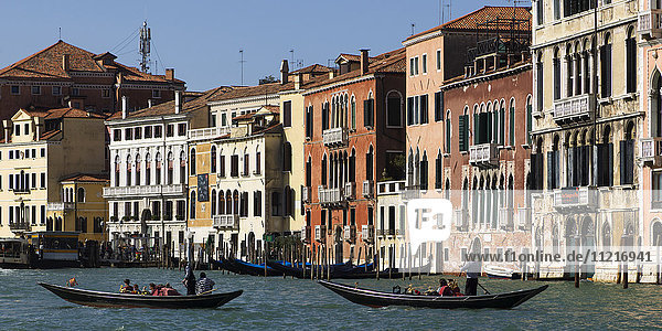Bunte Gebäude entlang eines Kanals mit Gondolieri in Gondeln; Venedig  Italien