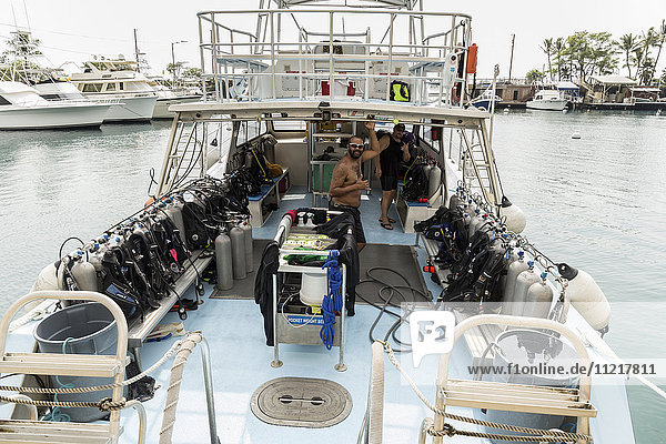 Divemaster  die für Jack's Diving Locker arbeiten  geben das Shaka-Handzeichen  während sie das Tauchboot M/V Kea Nui für die nächste Tauchfahrt im Hafen von Honokohau vorbereiten; Insel Hawaii  Vereinigte Staaten von Amerika