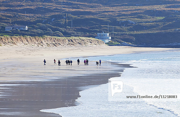 A group of people walking on the beach; Derrynane County Kerry Ireland