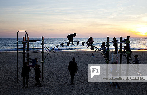 Kinder spielen auf einem Spielplatz am Strand bei Sonnenuntergang; Chiclana de la Frontera  Andalusien  Spanien