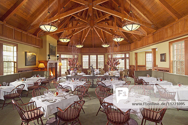 Großer Speisesaal mit mehreren Tischen und Holzdecken
